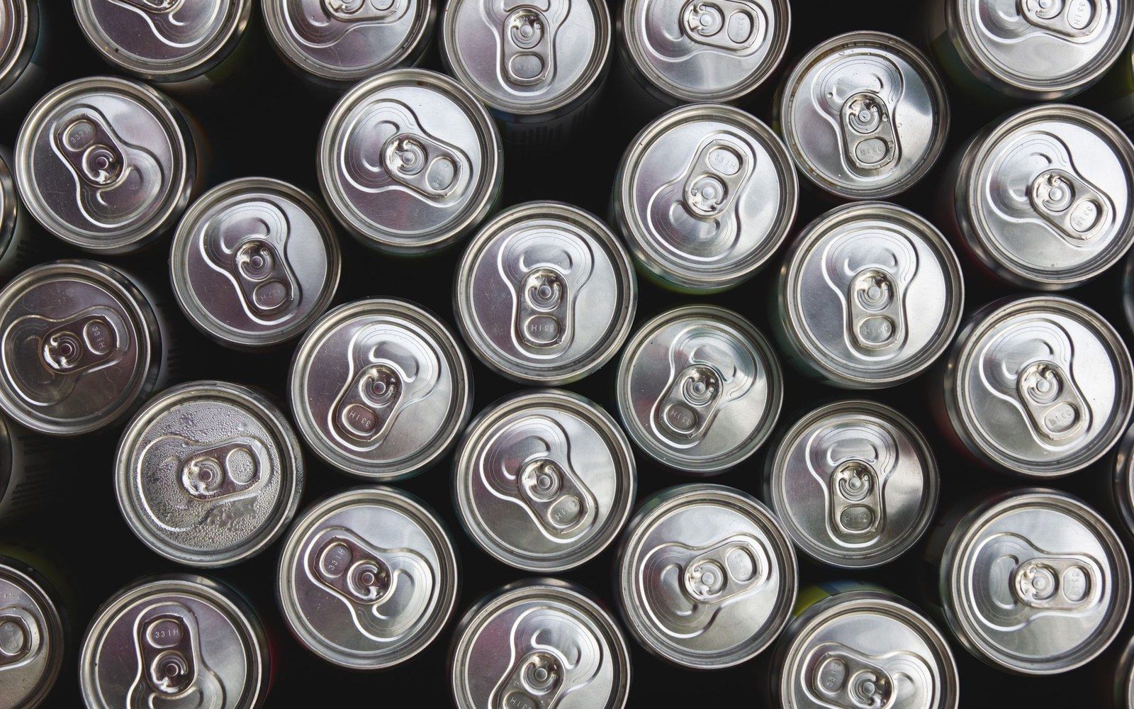 Overhead view of aluminum beverage cans packed tightly together with pull tabs facing up