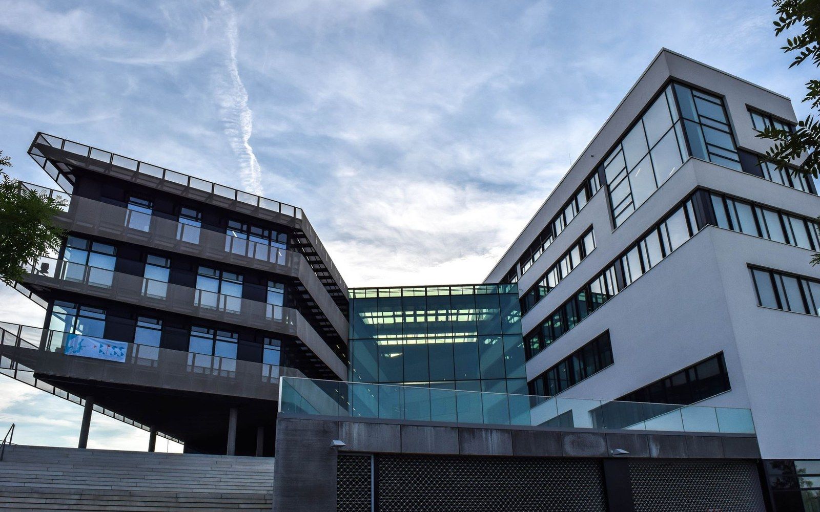 Modern office buildings with angular glass facades viewed from below against a cloudy sky