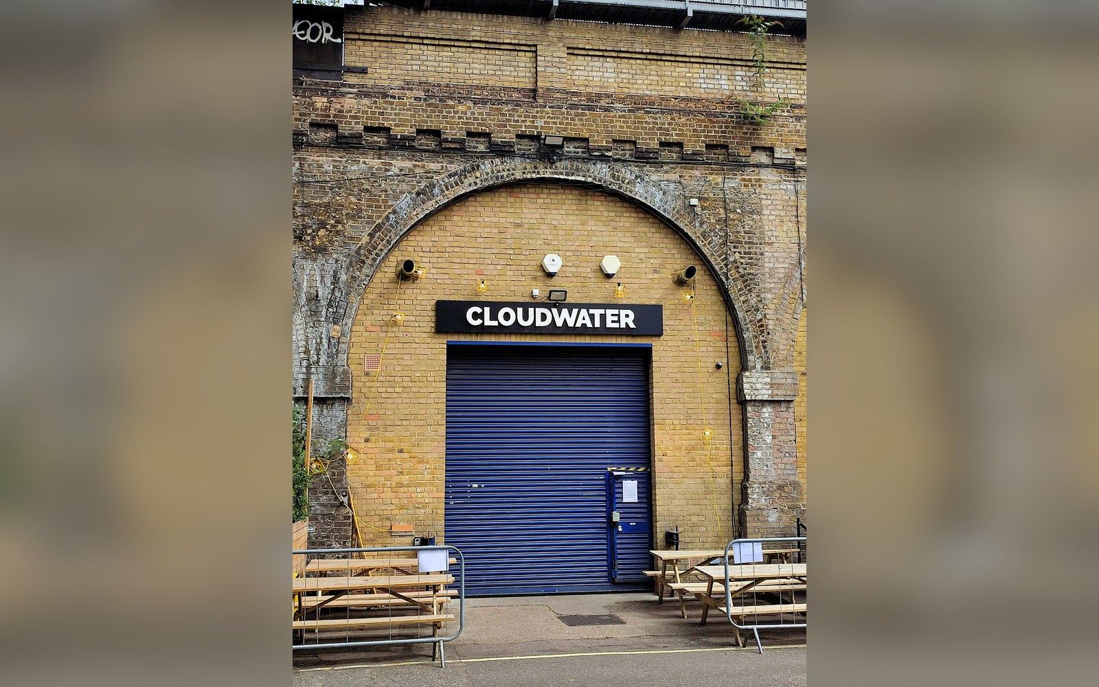 Cloudwater sign above a blue roller shutter door under a brick railway arch