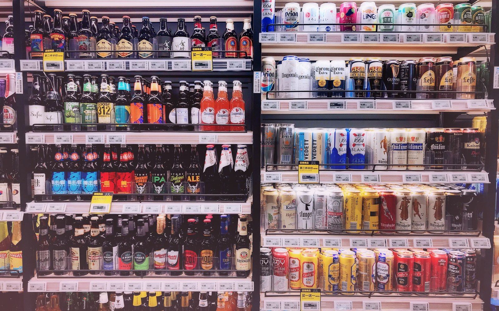 Store shelves stocked with rows of beer bottles and cans in various brands