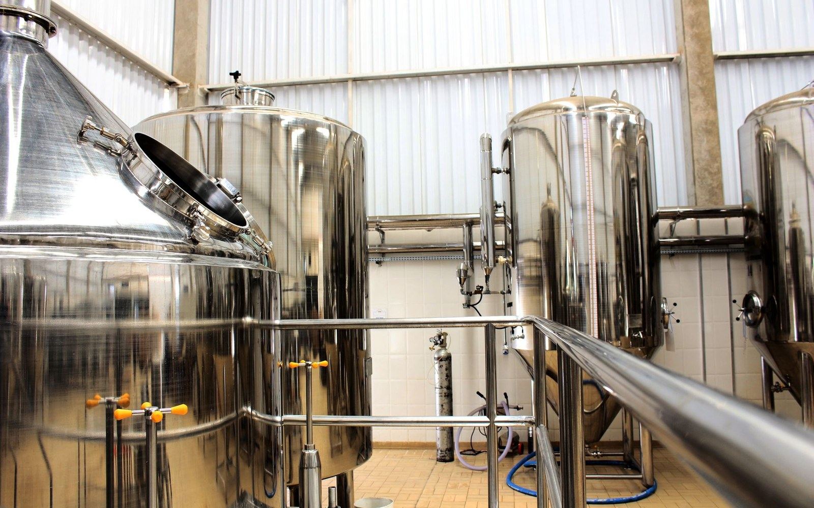 Stainless steel brewing tanks and pipework inside a small-scale brewery