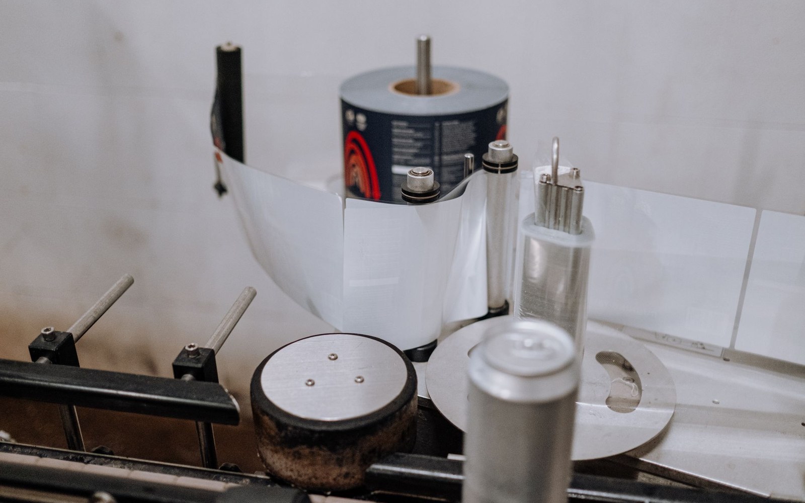 A roll of printed labels feeds through rollers on a labeling machine