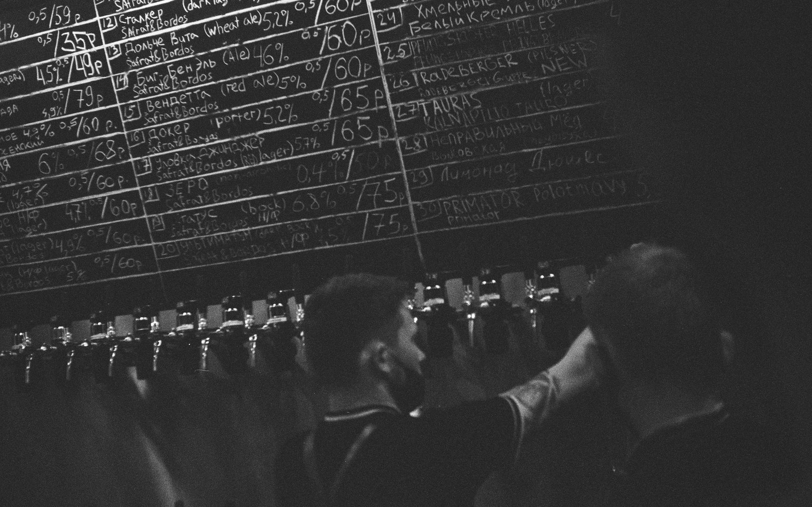 Taproom bar counter with a chalk tap-list board and a bartender
